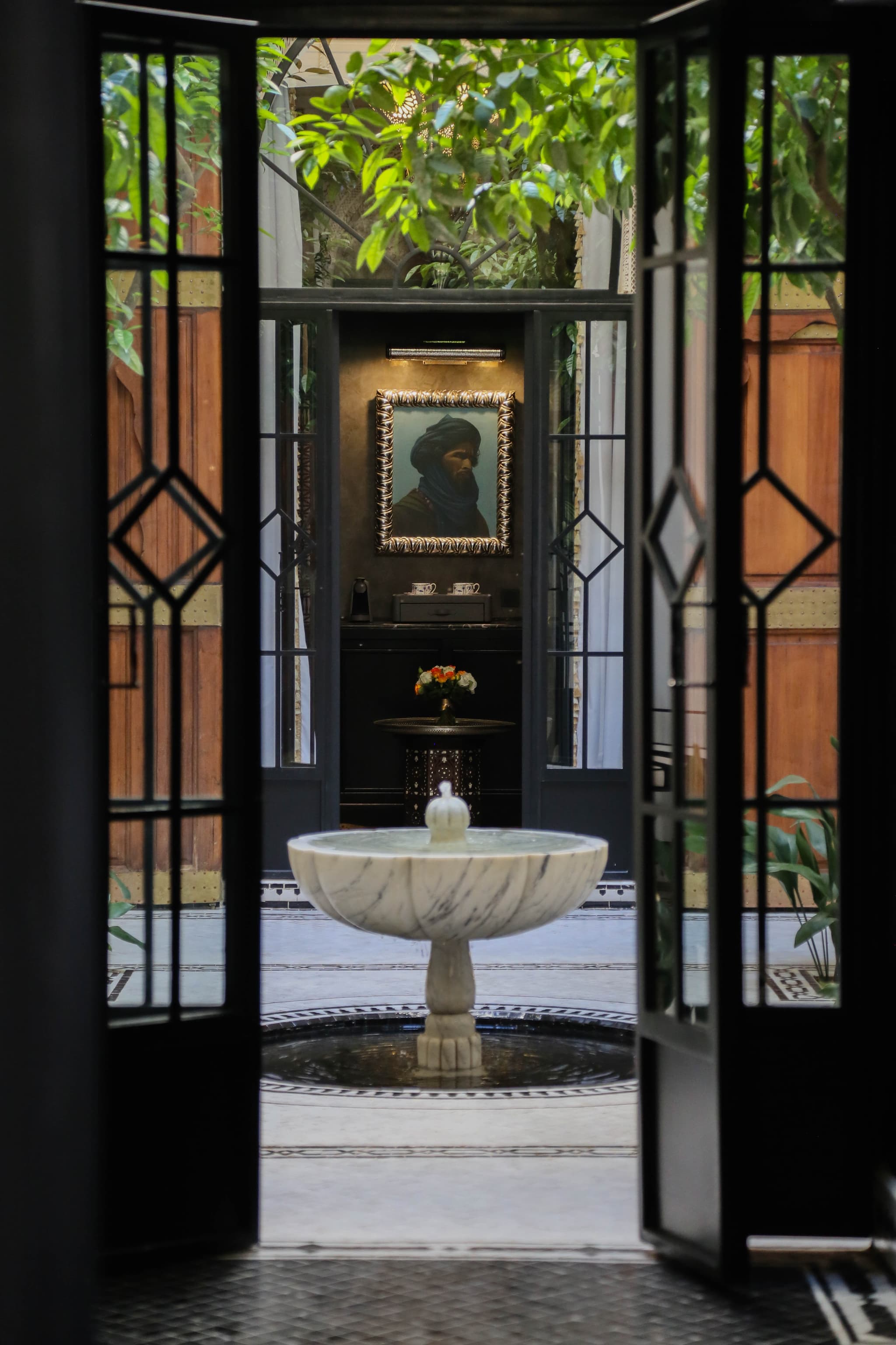 View through ornate Riad Sa'eed double doors onto the marble fountain and Tuareg portrait